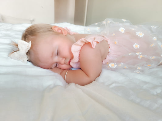 A sleeping infant wearing a pink daisy tutu romper.