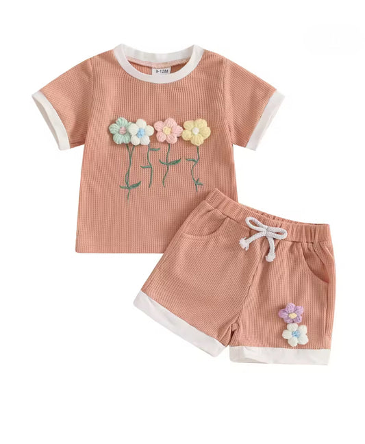 Children's outfit with pink striped shirt and shorts featuring floral designs on a white background