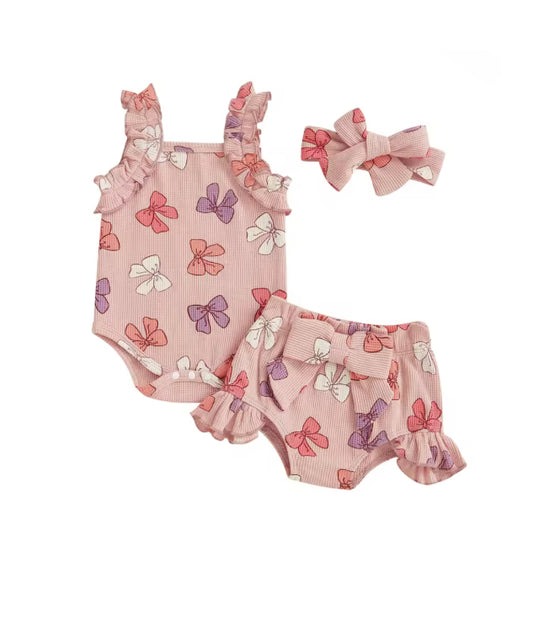 Baby outfit set with pink romper and bloomers featuring bow patterns, accompanied by a matching headband.