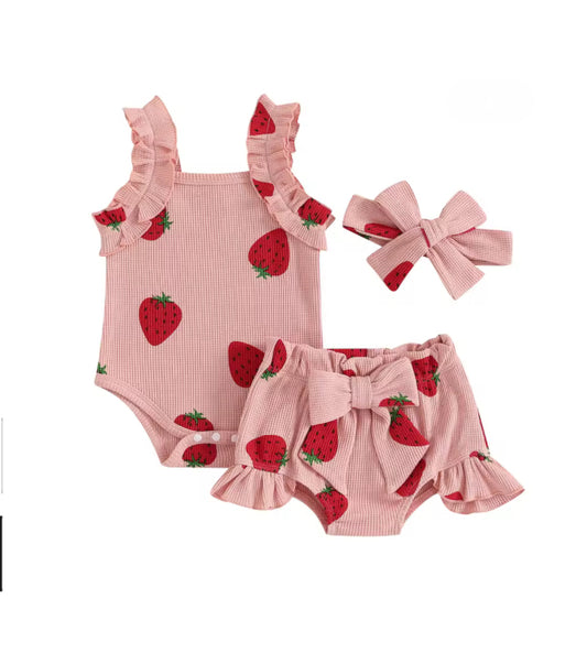 Pink baby outfit with strawberry pattern including romper and shorts on a white background