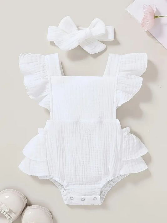 White baby romper with ruffled details and matching headband on a light background