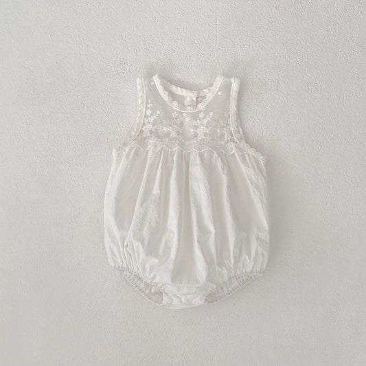 White baby romper with lace details on a light gray background