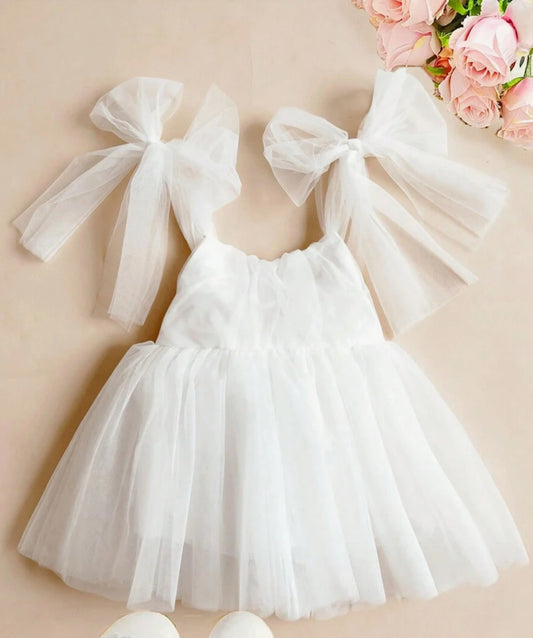 White tulle dress with large bows on a beige background
