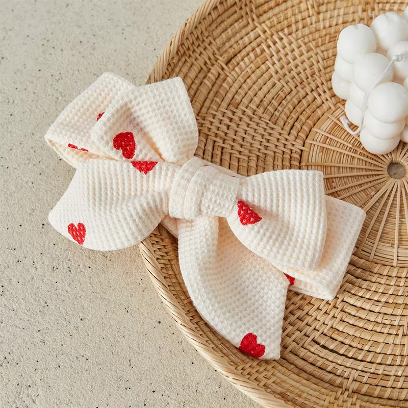 White bow with red heart details on a woven surface