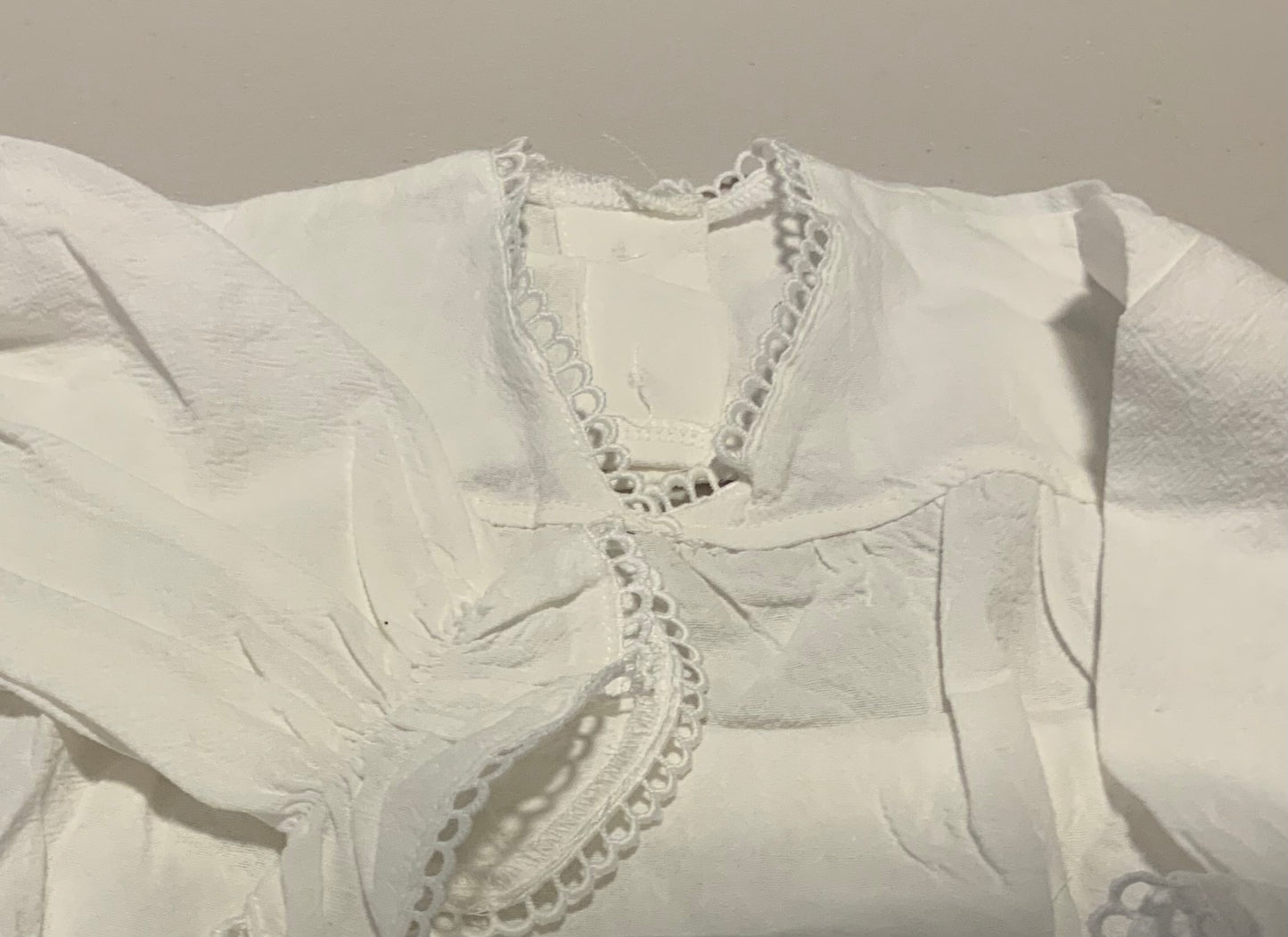 White blouse with lace details on a plain background