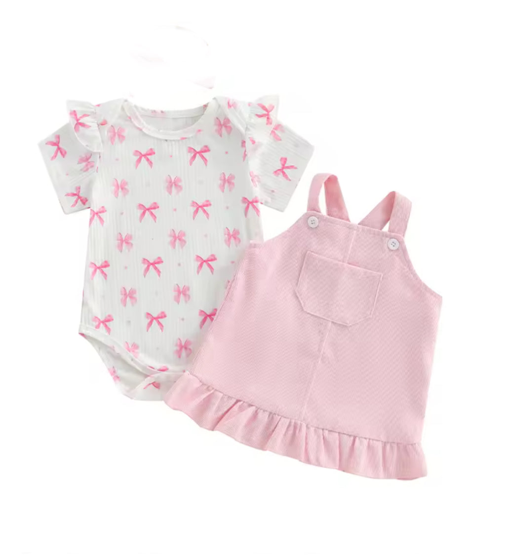 Baby outfit set with white romper with pink bows and pink overall dress on a white background