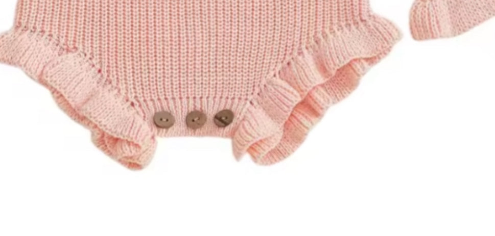Pink knitted baby romper with ruffled details on a white background