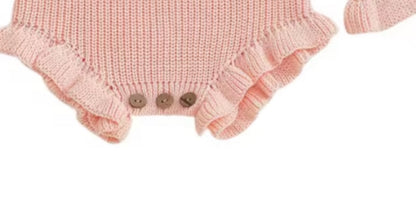 Pink knitted baby romper with ruffled details on a white background