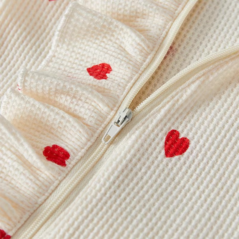 Close-up of a textured fabric with red heart patterns and a zipper.