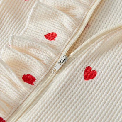 Close-up of a textured fabric with red heart patterns and a zipper.