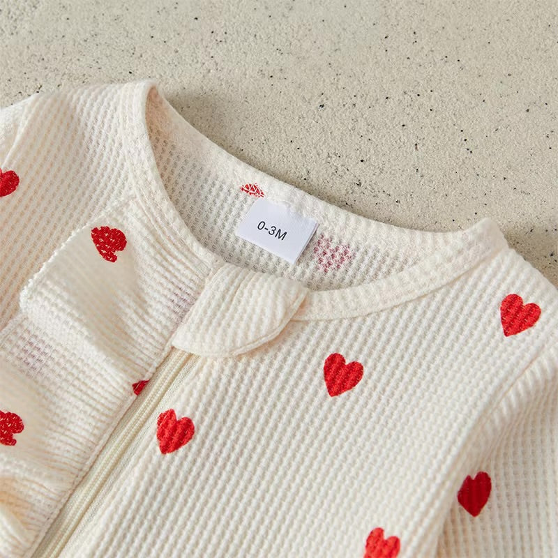 Baby outfit with red heart patterns on a textured surface