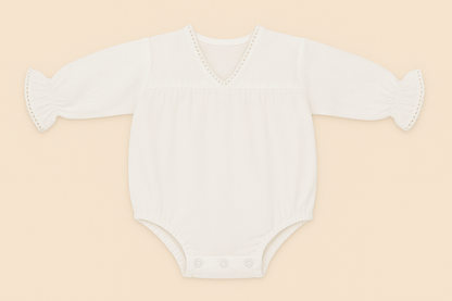 White baby onesie with ruffled sleeves on a beige background