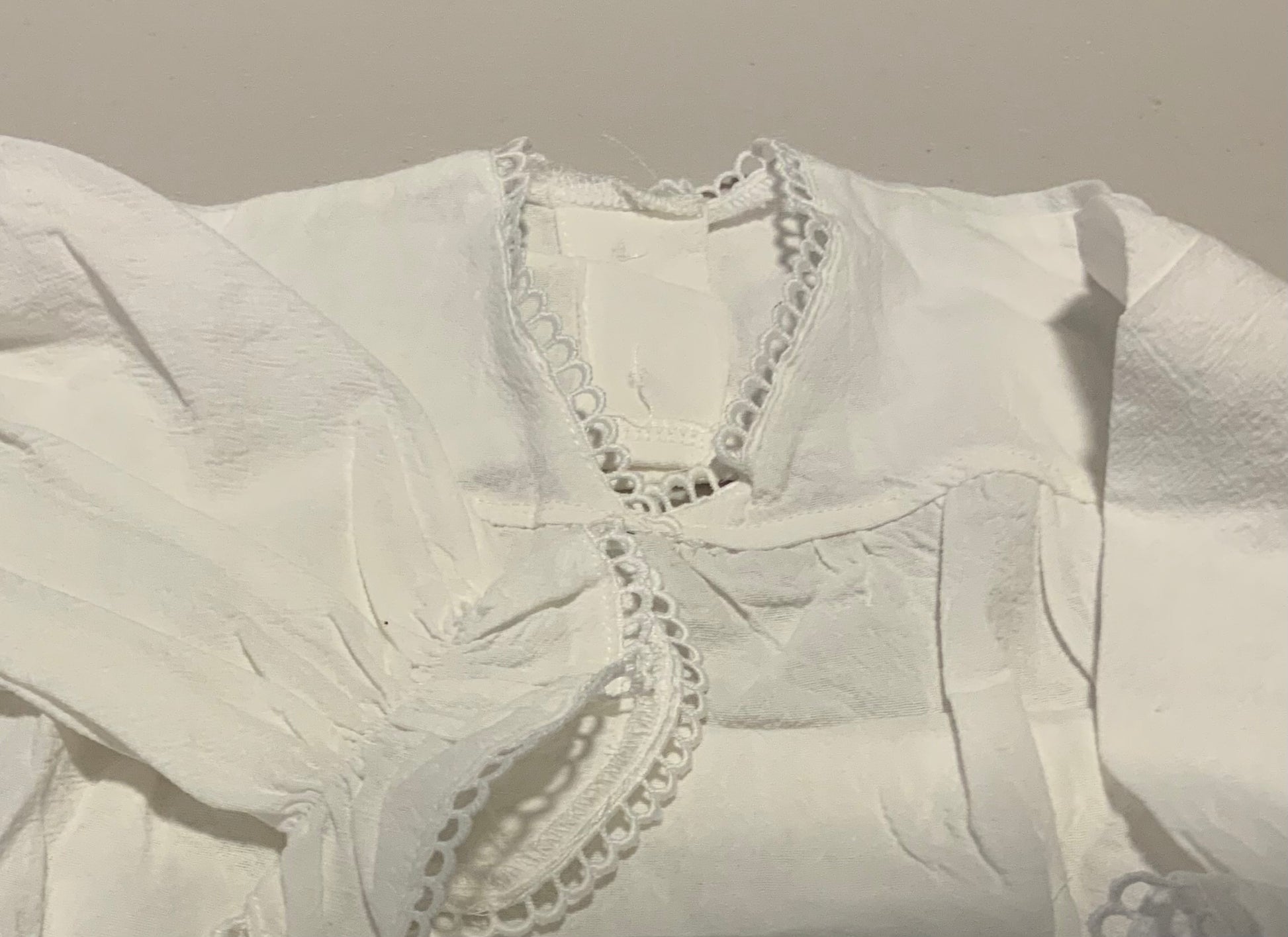 White blouse with lace details on a plain background
