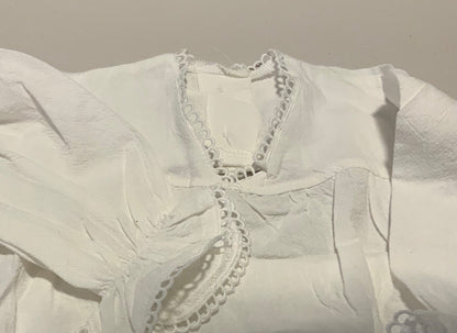 White blouse with lace details on a plain background