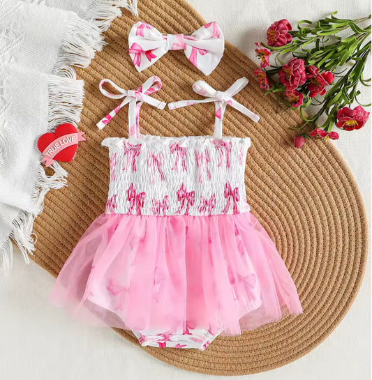 Pink and white children's swimsuit with matching headband on a woven mat with flowers.