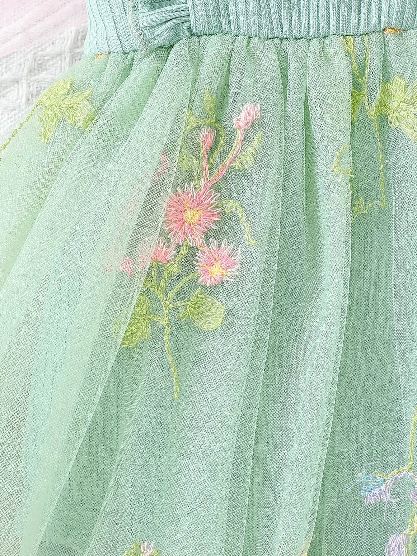 Green tulle skirt with floral embroidery on a light background