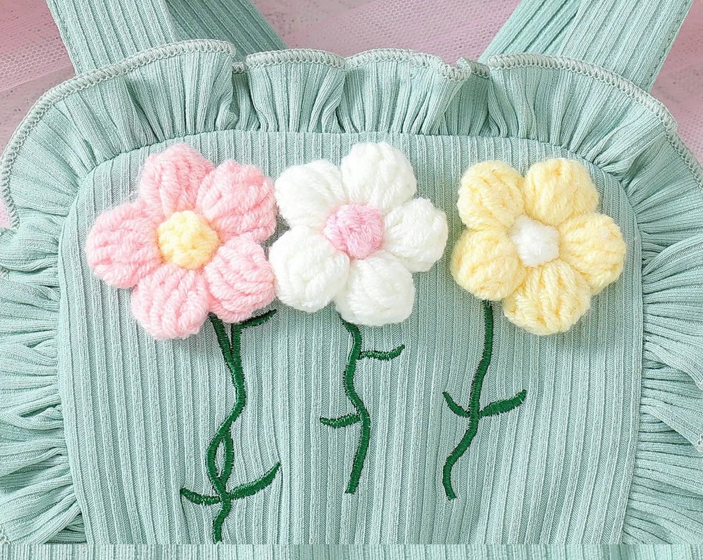Three knitted flowers on a textured green fabric background