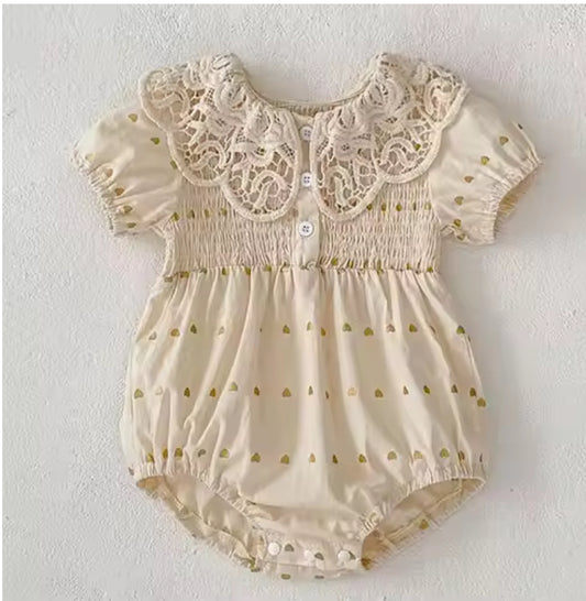 Beige baby romper with lace details on a white background