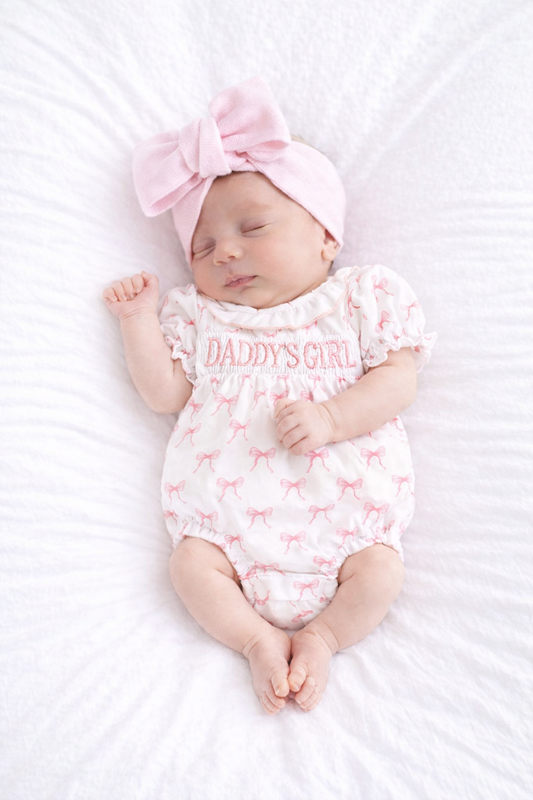 Baby girl’s clothing - Baby Boho -Baby wearing a 'Daddy's Girl' romper and pink headband on a white background
