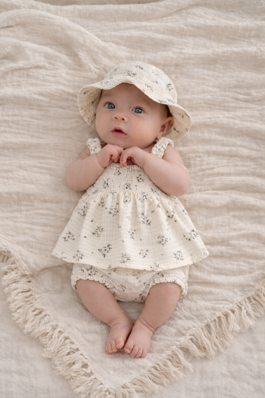 Baby boho - baby girls clothing -Baby in a floral dress and hat lying on a textured blanket