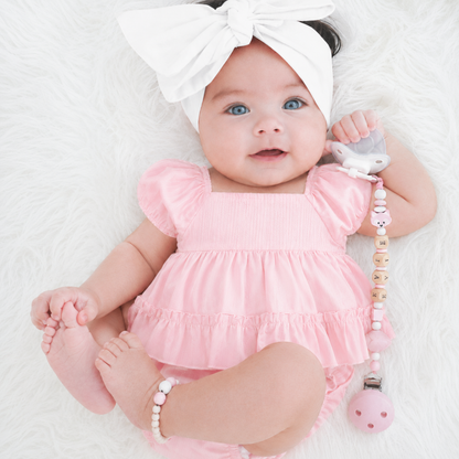 Baby in a pink outfit with a white headband by best baby store Baby Boho