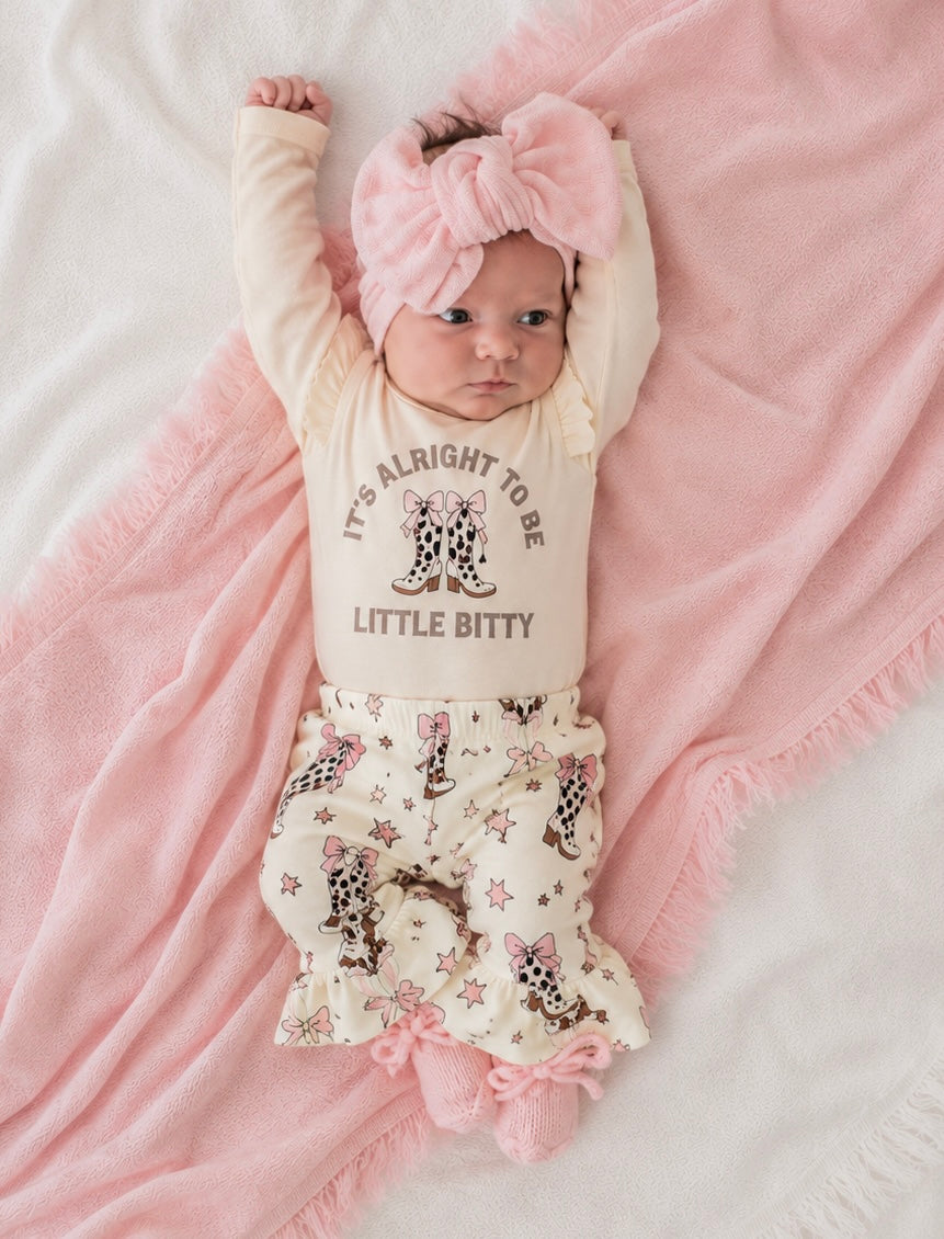 Baby wearing a onesie with text and a floral skirt on a pink blanket