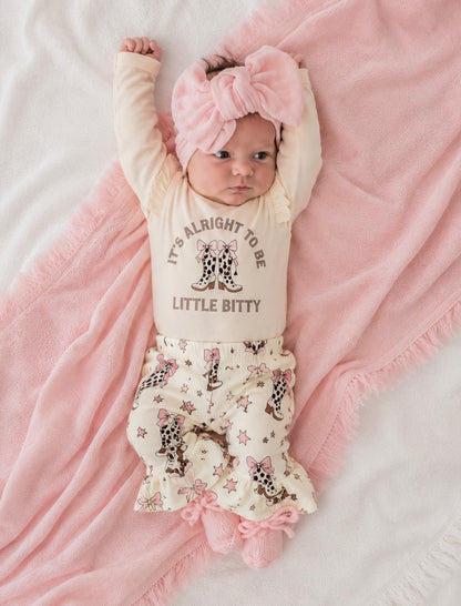 Baby wearing a onesie with text and a floral skirt on a pink blanket